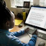 Young person using a wireless keyboard to work on a document in Microsoft Word on a large desktop monitor