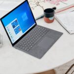 gray microsoft surface laptop computer on white table